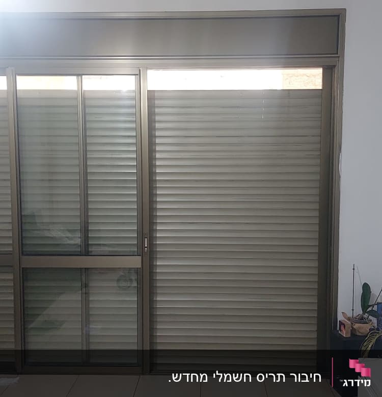 תריסים סגורים על חלון זכוכית גדול בחדר.